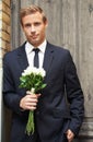 Dream guy. Portrait of a handsome man smiling and holding a bunch of white roses. Royalty Free Stock Photo