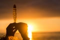 Dream life and hope future concept with close up of hands holding a feather with sunset sunlight in background doing silhouette - Royalty Free Stock Photo