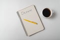 Dream reminder notice. Copybook with pen and cup of coffee on white background. Top view Royalty Free Stock Photo