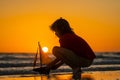 Dream of summer. Childhood concept. Kid boy holding tou boat. Cute little blond boy put toy boat in the sea water waves Royalty Free Stock Photo