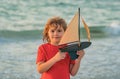 Dream of summer. Kid with toy boat in sea water on summer vacation. Little boy playing with toy seailing boat on sea Royalty Free Stock Photo