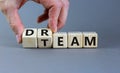 Dream team symbol. Businessman turns cubes and changes the word `dream` to `team`. Beautiful grey table, grey background. Busi Royalty Free Stock Photo