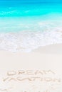 Dream written on sandy beach with soft ocean wave on background