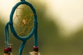 Dreamcatcher close-up on a background of green grass and blue sky. Blurred background