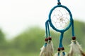 Dreamcatcher close-up on a background of green grass and blue sky. Blurred background