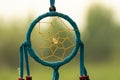 Dreamcatcher close-up on a background of green grass and blue sky. Blurred background.