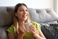 Dreamer girl relaxing on huge comfortable sofa holding hot drink in her hands Royalty Free Stock Photo