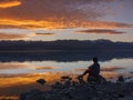 Dreamer, silhouette of woman sitting along the lake at sunset, human strength, psychology concept Royalty Free Stock Photo