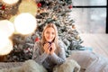 Dreamful cute teen girl near Christmas tree with cup of cacao. Kid wearing pajama dreaming near tree in the morning Royalty Free Stock Photo