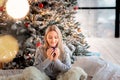 Dreamful cute teen girl near Christmas tree with cup of cacao. Kid wearing pajama dreaming near tree in the morning Royalty Free Stock Photo