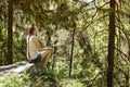 Dreaming beautiful girl sitting on a stone surrounded by coniferous forest on a sunny day Royalty Free Stock Photo
