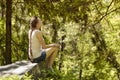 Dreaming beautiful girl sitting on a stone surrounded by coniferous forest on a sunny day Royalty Free Stock Photo