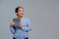 Dreaming beautiful mature grey haired woman in 50s holding digital tablet working or shopping online or checking on Royalty Free Stock Photo