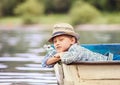 Dreaming boy lying in old boat on the river Royalty Free Stock Photo