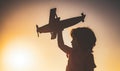 Dreaming boy with wooden plane. Kid boy playing with toy airplane at sunset. Child dreams of traveling and playing with Royalty Free Stock Photo