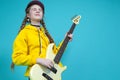 Dreaming Caucasian Teenager Guitar Musician Playing On Yellow Bass Guitar Posing In Fashionable Yellow Hoody Jacket Over Trendy