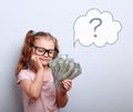 Dreaming cute kid girl in glasses looking on money and thinking Royalty Free Stock Photo