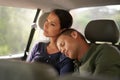 Dreaming of his next destination. An exhausted man sleeps on his wifes shoulder while they travel in a car.