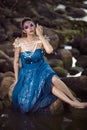 Relaxed Positive Lady Posing As Sea Mermaid  in Artistic Wet Blue Dress and Face Decorated with Strasses Holding Seashell in Hands Royalty Free Stock Photo