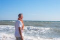 Dreaming man stands on the beach in surf line