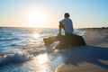 Dreaming traveler sits on a snag in the surf