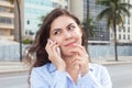 Dreaming woman in a blue blouse at phone at city Royalty Free Stock Photo