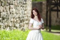 Dreaming Young Lady in White Dress and Red hair. Posing Against Ancient Castle Royalty Free Stock Photo