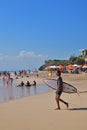 Young foreign surfer with board to catch big sea wave to surf with other tourists at Dreamland Beach, South Kuta, Bali, Indonesia