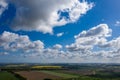 dreamlike blue sky with white sheep clouds over green and yellow fields Royalty Free Stock Photo