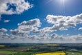 Dreamlike blue sky with white sheep clouds over green and yellow fields Royalty Free Stock Photo