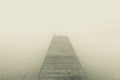 Dreamlike image of wooden jetty on lake in fog