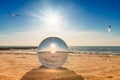 dreamlike seashore in the backlight with seagulls and a glass ball in the foreground Royalty Free Stock Photo