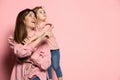 Dreams. Portrait of young woman and little girl, mother and daughter isolated on pink studio background. Mother& x27;s
