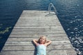 Dreams and relaxation. Girl child with closed eyes lying on wooden lake dock on sunny day. Kid dreaming enjoying summer outdoors. Royalty Free Stock Photo