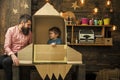 Dreams of space. Kid happy sit in cardboard hand made rocket. Boy play with dad, father, little cosmonaut sit in rocket Royalty Free Stock Photo