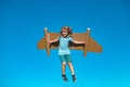 Dreams of travel. Child flying on jetpack with toy airplane on sky background. Happy child boy playing in cardboard Royalty Free Stock Photo