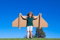 Dreams of travel. Child flying on jetpack with toy airplane on sky background. Happy child playing in cardboard plane Royalty Free Stock Photo