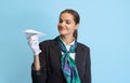 Half-length portrait of beautiful young girl, flight attendant in black uniform posing isolated on blue studio