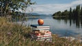 Stack of books in grass by lake for summer reading with red delicious apple on top. Royalty Free Stock Photo