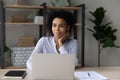 Dreamy African American businesswoman sitting at desk with laptop Royalty Free Stock Photo