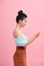 Dreamy asian beauiful young woman holds modern electronic device, isolated over pink background