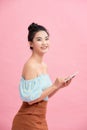 Dreamy asian beauiful young woman holds modern electronic device, isolated over pink background