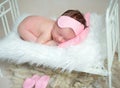 Dreamy baby girl lying curled on stomach on small crib. Royalty Free Stock Photo
