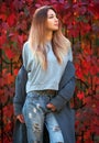 Dreamy beautiful girl with long colorful hair on autumn background of red grape hedge. Inspired woman in gray coat. Autumn Royalty Free Stock Photo