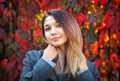 Dreamy beautiful girl with long colorful hair on autumn background of red grape hedge. Inspired woman in gray coat. Autumn Royalty Free Stock Photo