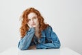 Dreamy beautiful girl thinking dreaming sitting at table over white background. Royalty Free Stock Photo