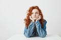 Dreamy beautiful girl thinking dreaming sitting at table over white background. Royalty Free Stock Photo