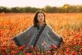 Dreamy beautiful woman relaxing in red poppy meadow.