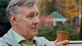 Dreamy calm gray-haired elderly pensioner man grandfather middle aged adult male person sitting on autumn park bench Royalty Free Stock Photo