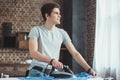 dreamy caucasian teenager ironing blue shirt